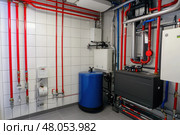 House heating system equipment. Pipelines. Basement mechanical room with condensing water heater, storage tank, plumbing systems. Plumbing service. Pipeline in boiler room. Pipes. Wall installation. Стоковое AI-изображение, AI-художник Марина Демидюк / Фотобанк Лори