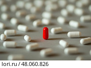 Red capsule stands out among white tablets on a plain surface. Красная капсула, таблетка выделяется среди белых таблеток на ровной поверхности. Стоковое AI-изображение, AI-художник Katsiaryna Repich / Фотобанк Лори