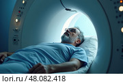 Мужчина средних лет лежит внутри аппарата МРТ. Стоковое AI-изображение, AI-художник Илья Старков / Фотобанк Лори