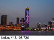 Shanghai, China - 1 April 2025: Night view of glowing Pudong skyline across the Huangpu River, illuminated skyscrapers reflecting on water. Редакционное фото, фотограф Татьяна Терехина / Фотобанк Лори
