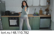 Brunette woman dance, have fun at home listens song, moves to music, feels overjoyed, celebrate good news, relish carefree life looks happy. Young adult female twirls, grooves. Lady dancing in kitchen. Стоковое видео, видеограф Марина Демидюк / Фотобанк Лори