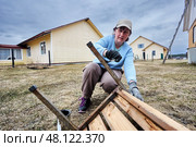 Brushing protective paint onto metal legs of garden bench, dedicated outdoor renovator works methodically, intent on sealing each joint and surface. Стоковое фото, фотограф Владимир Григорьев / Фотобанк Лори
