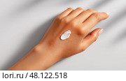Female hand applying cream on arm for hydration and skin care in natural light. Женская рука наносит крем на руку для увлажнения и ухода за кожей в естественном свете. Стоковое AI-изображение, AI-художник Katsiaryna Repich / Фотобанк Лори