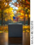 A voting box with an American flag stands out amid colorful autumn trees, capturing a peaceful election season vibe. Стоковое AI-изображение, AI-художник Данила Большаков / Фотобанк Лори