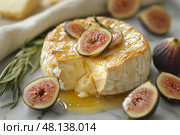 Creamy brie cheese topped with fresh figs and honey on a marble surface. Сливочный сыр бри со свежим инжиром и медом на мраморной поверхности. Стоковое AI-изображение, AI-художник Katsiaryna Repich / Фотобанк Лори