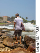 Surfer Walking on Rocks Along the Beach, Embracing the Spirit of Adventure and Freedom. Стоковое фото, фотограф Женя Канашкин / Фотобанк Лори