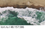 Aerial view capturing emerald green waves breaking over golden sand, white foam cascading along pristine coastal landscape with serene marine scenery. Стоковое видео, видеограф ILIA GOROKHOV / Фотобанк Лори