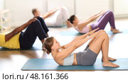 Young woman with multinational athletes group raise and lower torso. Стоковое видео, видеограф Яков Филимонов / Фотобанк Лори
