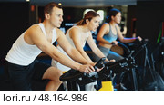 Determined young guy training with spin bike in fitness hall during full-body workout. Стоковое видео, видеограф Яков Филимонов / Фотобанк Лори