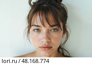 Serious brunette woman with green eyes hair bun and fringe posing bare shouldered against light wall clean natural skincare portrait. Стоковое AI-изображение, AI-художник Павел Муравьев / Фотобанк Лори
