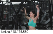 In gym, woman uses lat pulldowm machine to strengthen arm muscles. Стоковое видео, видеограф Яков Филимонов / Фотобанк Лори