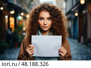 On street beautiful woman stands grasping blank sign made of white paper in hands. With sign she has the opportunity to convey her thoughts or messages, using blank canvas to express her creativity and capture attention. Стоковое AI-изображение, AI-художник Данила Большаков / Фотобанк Лори