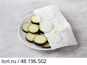 Drying of slices eggplants with a paper towel on a gray textured background. Processing eggplant before cooking, removing bitterness. Стоковое фото, фотограф Ольга Лепёшкина / Фотобанк Лори