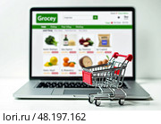 Клавиатура ноутбука с маленькой тележкой из супермаркета. Покупка продуктовых и промышленных товаров в интернет магазинах онлайн. A laptop keyboard with a small supermarket cart. Purchase of grocery and industrial goods in online stores online. Стоковое AI-изображение, AI-художник Гер Олег / Фотобанк Лори