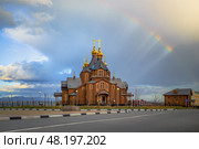 Кафедральный собор Святой Живоначальной Троицы, город Анадырь, Чукотский автономный округ (Чукотка), Россия. Радуга и солнечные лучи над собором. Вид на красивую деревянную православную церковь с золотыми куполами и крестами. Живописный летний городской пейзаж с христианским храмом. Русская православная церковь в Сибири и на Дальнем Востоке России. Стоковое фото, фотограф Андрей Степанов / Фотобанк Лори