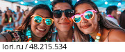 Three friends happily pose together with neon sunglasses and vibrant accessories during a summer festival. Стоковое AI-изображение, AI-художник Данила Большаков / Фотобанк Лори