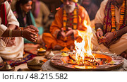 Devotees perform a sacred ritual around a fire in a vibrant indoor setting, embracing tradition and spirituality. Стоковое AI-изображение, AI-художник Данила Большаков / Фотобанк Лори