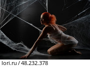 Red-haired woman trapped in a delicate web of white strands in dark setting. Стоковое фото, фотограф Гурьянов Андрей / Фотобанк Лори