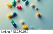 Colorful assortment of pills are scattered across a blue background. Стоковое AI-видео, аниматор Sergey Grishin / Фотобанк Лори
