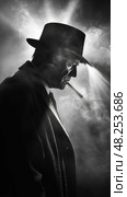 A man in a fedora smokes a cigarette, standing in a foggy, backlit environment. Стоковое AI-изображение, AI-художник Данила Большаков / Фотобанк Лори