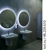Interior of modern public toilet with white sinks and round mirrors. Стоковое фото, фотограф Евгений Харитонов / Фотобанк Лори