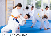 Karate training - girl and boy of different nationalities in pairs exercising karate movements during group training in gym. Стоковое фото, фотограф Яков Филимонов / Фотобанк Лори