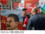 Мужчина держит плакат с портретом Иосифа Сталина на фоне праздничных баннеров приуроченных к празднованию 80-летия Победы в Великой Отечественной войне, Россия. Редакционное фото, фотограф Николай Винокуров / Фотобанк Лори