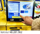 Kirov, Russia - March 05, 2025: Customer using self-checkout kiosk at supermarket to finalize payment for groceries in Russia. Редакционное фото, фотограф Кривошеина Елена Леонидовна / Фотобанк Лори