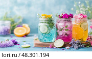Summer Refreshments: Three Colorful Infused Water Jars with Flowers and Fruits. Стоковое AI-изображение, AI-художник Данила Большаков / Фотобанк Лори