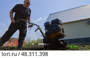 a farmer plows the land with a miniature cultivator tractor, which has impressive power and the ability to work on difficult soils. Стоковое фото, фотограф Скрипачев Антон / Фотобанк Лори
