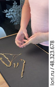 A woman reviewing jewelry, laying out a gold-colored necklace, bracelet, earrings, and ring on a table. Vertical video. Oblique Angle. Стоковое видео, видеограф Vadzim Yakubovich / Фотобанк Лори