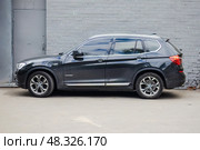 SUV BMW X3 parked in front of gray brick building, side view. Редакционное фото, фотограф Константин Григорьев / Фотобанк Лори