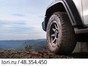 The concept of road trips and adventure tours on SUVs and cars in nature. A large wheel of an SUV on top of a mountain in close-up against the sky and space, the spirit of freedom. Стоковое фото, фотограф Владимир Разгуляев / Фотобанк Лори