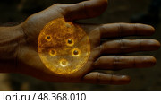 An outstretched hand reveals a luminous circular figure with dots, casting an intriguing glow in a softly lit setting. Стоковое AI-изображение, AI-художник Данила Большаков / Фотобанк Лори