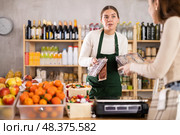 Woman store employee offers customer to choose sweets, shows packed various dessert options. Стоковое фото, фотограф Яков Филимонов / Фотобанк Лори