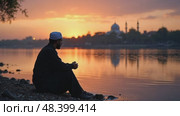 A lone mourner sitting by a river at twilight, his reflection blurred in the water as he whispers prayers for the martyrs of Karbala. Стоковое AI-видео, аниматор Sergey Grishin / Фотобанк Лори