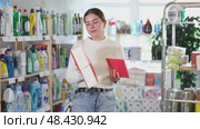 Young European woman choosing packages of square and rectangular napkins in a household chemicals store. Стоковое видео, видеограф Яков Филимонов / Фотобанк Лори