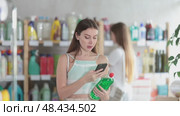 European woman scans a barcode on her mobile for washing dishes against the background of other visitors to the household department of the supermarket. Buyer pays for purchases using a QR code. Стоковое видео, видеограф Яков Филимонов / Фотобанк Лори
