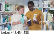 Before buying in household shop, African male customer with European wife choose glass cleaner spray. Стоковое видео, видеограф Яков Филимонов / Фотобанк Лори