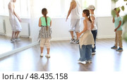 Preteen children enthusiastically following male instructor moves during group hip-hop lesson in sunlit mirrored studio, mastering modern street dance choreography. Стоковое видео, видеограф Яков Филимонов / Фотобанк Лори