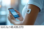 A woman uses a smartphone while wearing a digital health patch on her arm, representing wearable tech, health monitoring, and the future of personal medical data interaction. Стоковое AI-изображение, AI-художник Ольга Сухарева / Фотобанк Лори