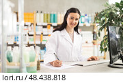 Middle-aged female pharmacist restocking with paper in drugstore. Стоковое фото, фотограф Яков Филимонов / Фотобанк Лори