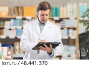 Man pharmacist makes restock, uses electronic carrier tablet of information. Стоковое фото, фотограф Яков Филимонов / Фотобанк Лори