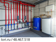 House heating system equipment. Pipelines. Basement mechanical room with condensing water heater, storage tank, plumbing systems. Plumbing service. Pipeline in boiler room. Pipes. Wall installation. Стоковое AI-изображение, AI-художник Марина Демидюк / Фотобанк Лори