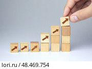Hand putting wooden cube with icon percentage symbol. Interest rate, financial stocks, mortgage concept. Wooden blocks with percent sign. Growing arrow graph. Light gray background. Inflation, budget. Стоковое AI-изображение, AI-художник Марина Демидюк / Фотобанк Лори
