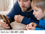Father and son little boy laughing and using phone. They watching funny videos together, playing games on smartphone. Concept technology, smart phone addicted. Fun weekend activity. Modern fatherhood. Стоковое фото, фотограф Марина Демидюк / Фотобанк Лори