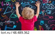 Child's colorful Drawing Creation: A kid with blonde hair drawing with crayon on a blackboard, learning, playing concept. Стоковое AI-изображение, AI-художник Данила Большаков / Фотобанк Лори