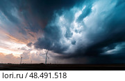 Dark shelf cloud preceding a severe thunderstorm at a wind turbine park. Beautiful thunderstorm black clouds and clouds hanging over the ground. Стоковое AI-изображение, AI-художник ALLA YURTAYEVA / Фотобанк Лори