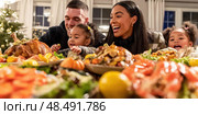 A family of four is gathered around a table full of food. Стоковое AI-изображение, AI-художник Ярославский Максим / Фотобанк Лори