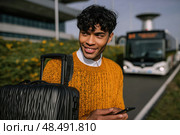 A man is smiling and holding a suitcase and a cell phone. Стоковое AI-изображение, AI-художник Ярославский Максим / Фотобанк Лори